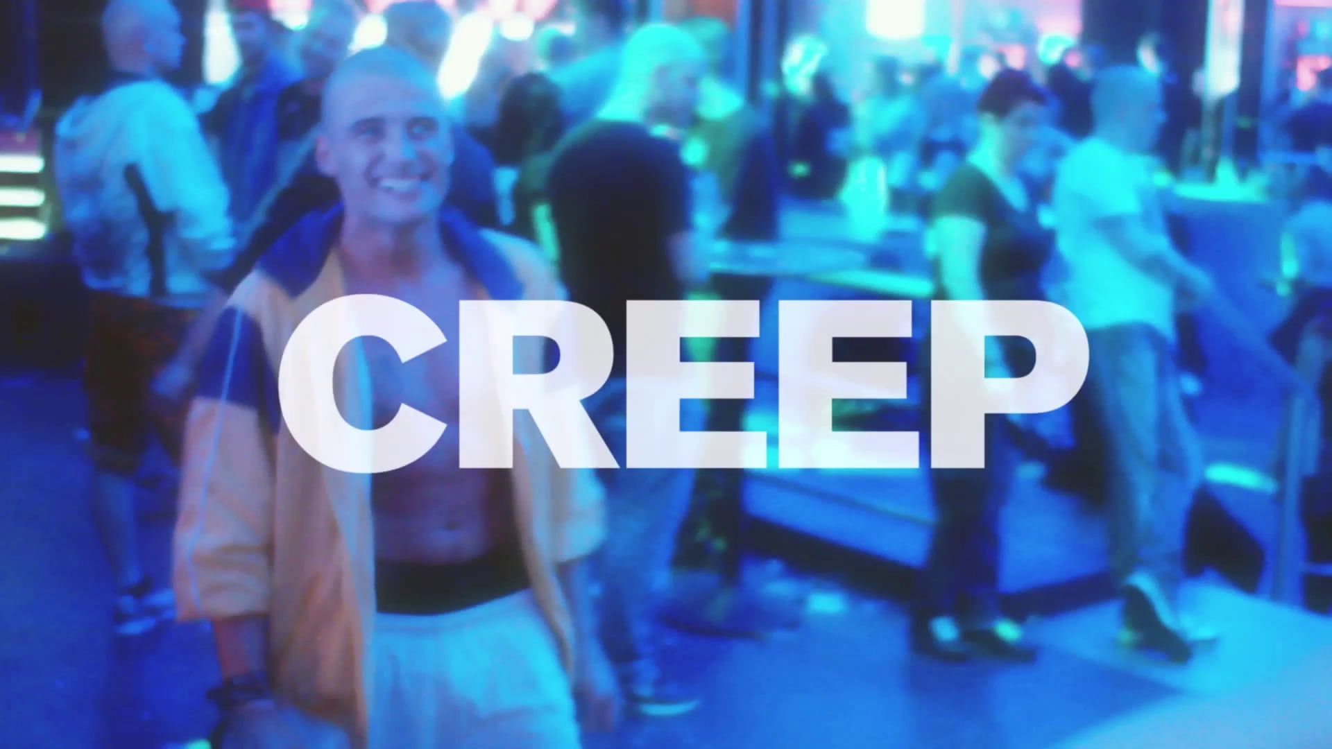 A man in an open tracksuit jacket grins at the camera on a blue-lit dance floor, the word CREEP across the frame.